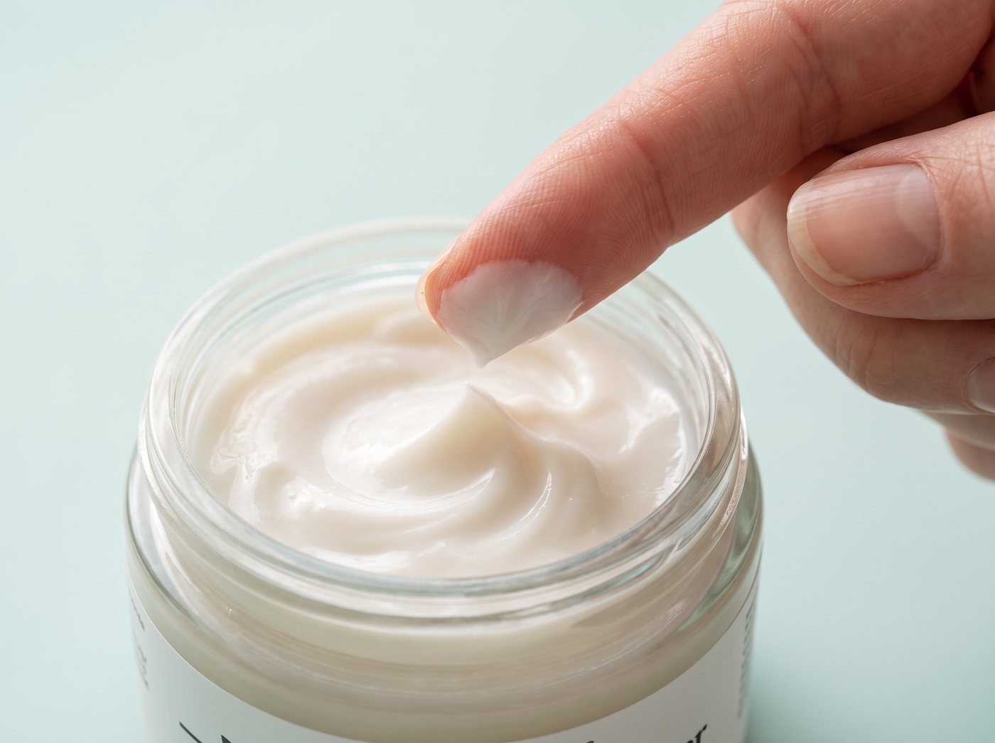 Fingertip scooping the light, silky Zafra cream from the jar